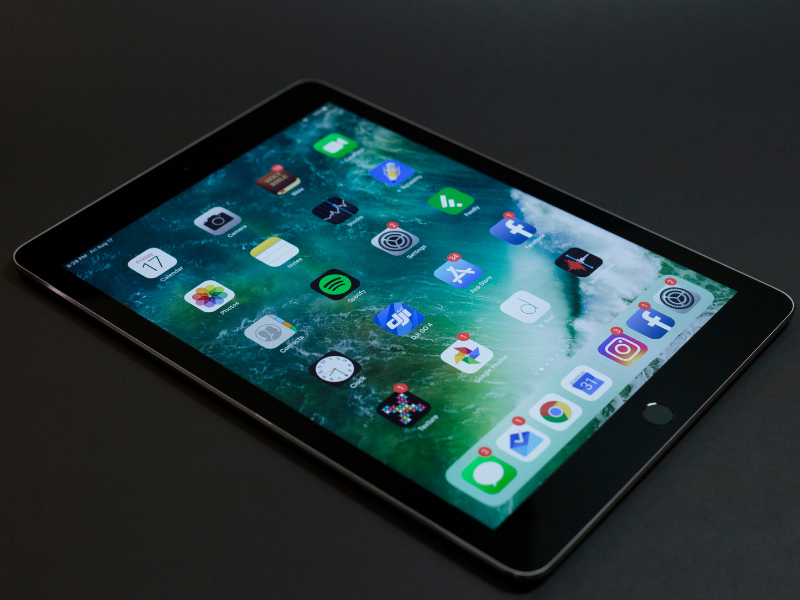 A tablet displaying various app icons on a green background
