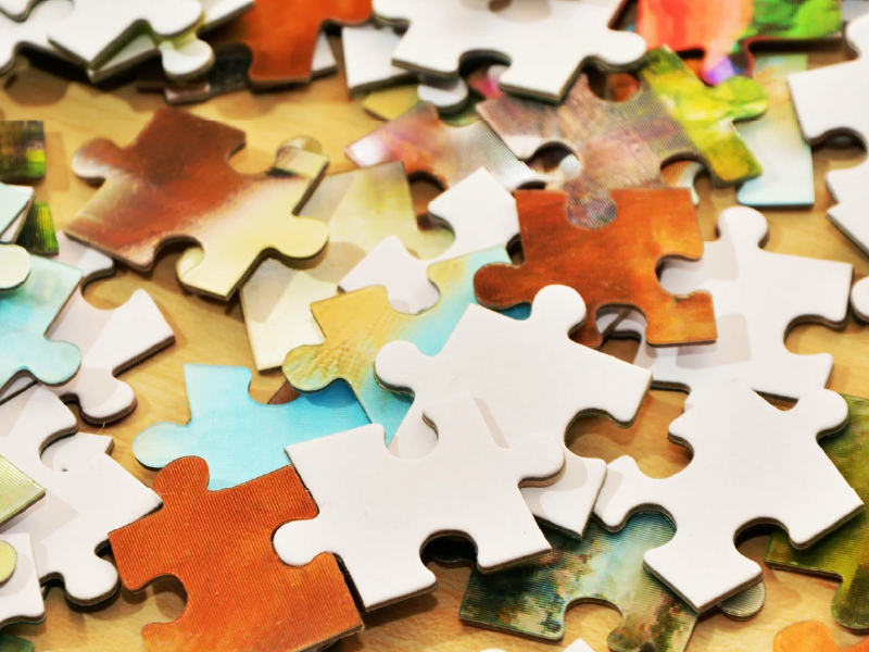 Colorful jigsaw puzzle pieces scattered on a wooden surface
